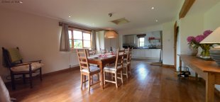 Spacious cooking area / dining room with pine floors & patio doorways to garden